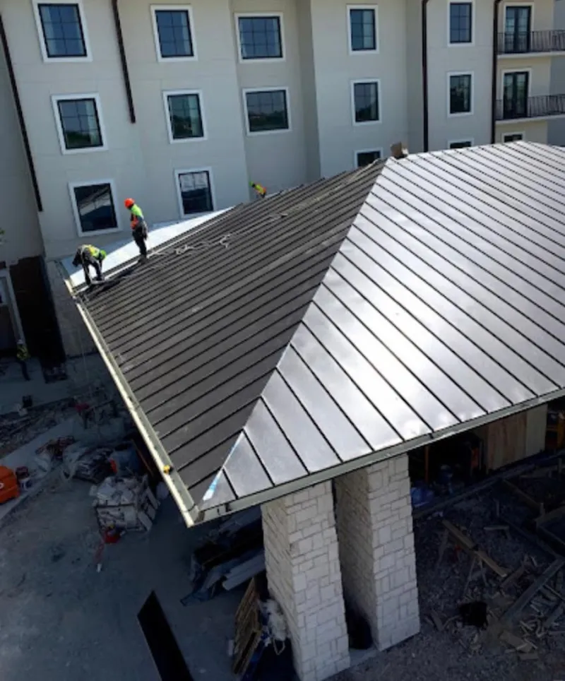 Crew installing standing seam metal roof panels on a commercial project in Converse